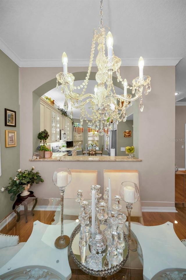 dining space with wood-type flooring, crown molding, and a notable chandelier