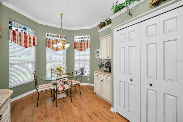 dining space featuring ornamental molding and light hardwood / wood-style flooring