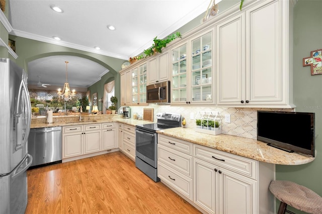 kitchen featuring pendant lighting, appliances with stainless steel finishes, sink, light hardwood / wood-style flooring, and crown molding