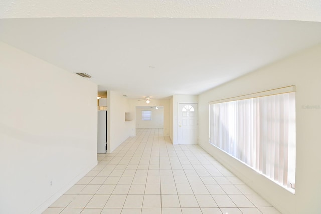 unfurnished room featuring light tile patterned flooring, ceiling fan, a wealth of natural light, and a textured ceiling