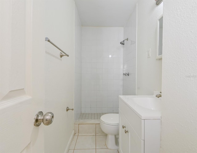 bathroom with toilet, tile patterned flooring, a tile shower, and vanity