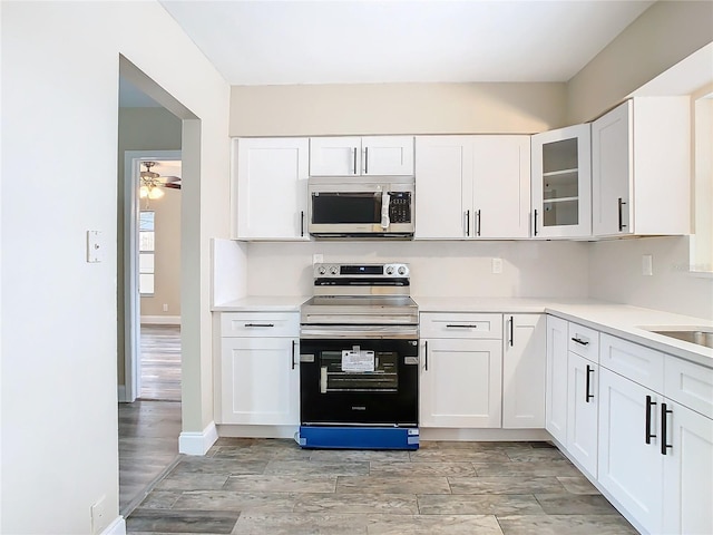 kitchen with light hardwood / wood-style flooring, ceiling fan, appliances with stainless steel finishes, sink, and white cabinets