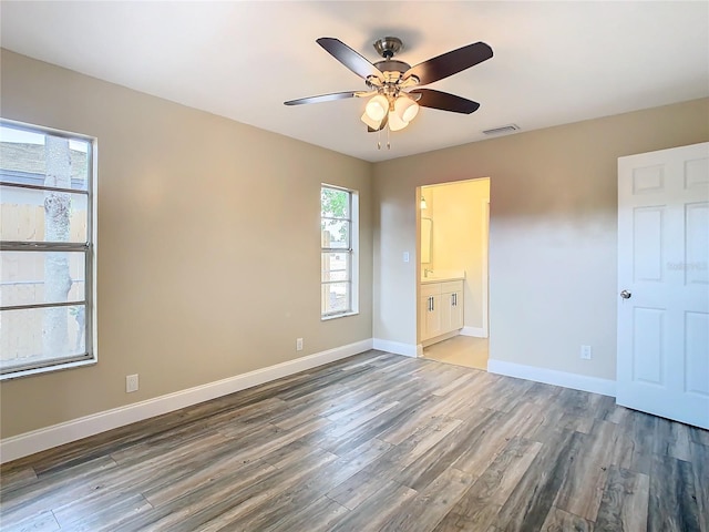 unfurnished bedroom with ceiling fan, wood-type flooring, and ensuite bath