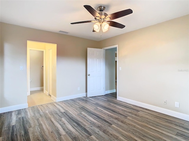 unfurnished bedroom with ceiling fan and dark wood-type flooring