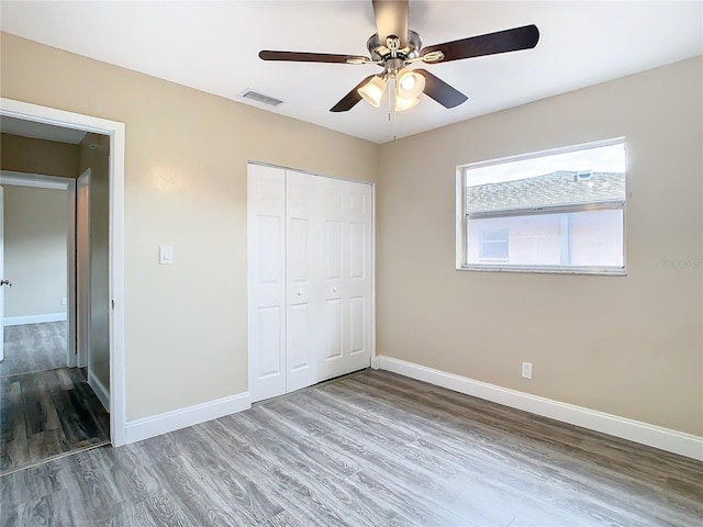 unfurnished bedroom featuring hardwood / wood-style flooring, a closet, and ceiling fan