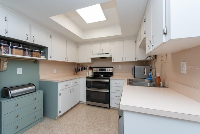 kitchen featuring double oven range, white cabinetry, a tray ceiling, and sink