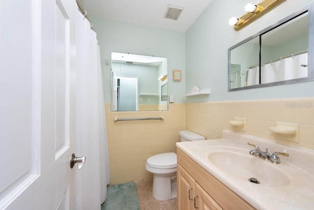 bathroom with tile walls, toilet, and vanity