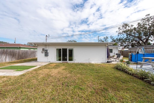 back of property featuring a fenced in pool, a yard, and a patio