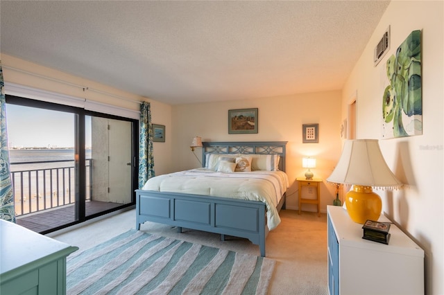 bedroom with access to exterior, light colored carpet, a textured ceiling, and a water view