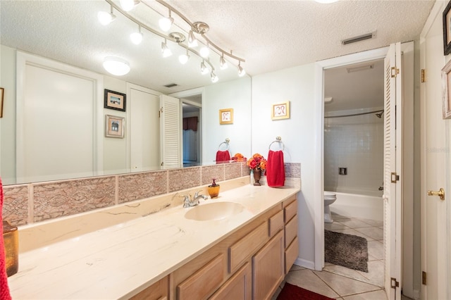 full bathroom with a textured ceiling, tiled shower / bath combo, tile patterned flooring, vanity, and toilet