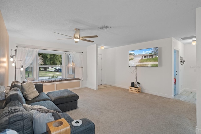 living room featuring light carpet, ceiling fan, and a textured ceiling