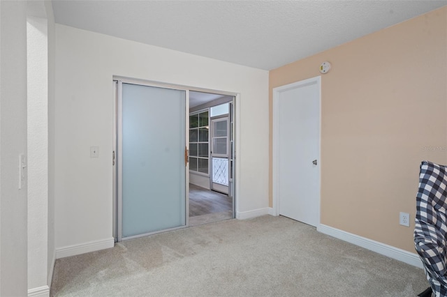 unfurnished room with light colored carpet and a textured ceiling