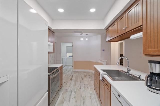 kitchen featuring sink, light hardwood / wood-style floors, and white appliances