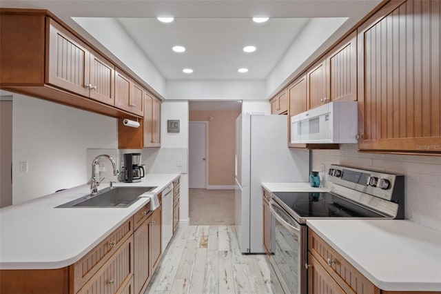 kitchen with backsplash, sink, white appliances, and light hardwood / wood-style floors