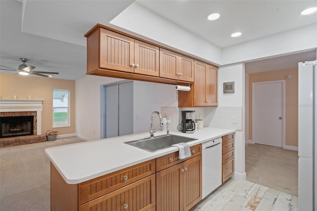 kitchen with kitchen peninsula, ceiling fan, white appliances, a fireplace, and sink