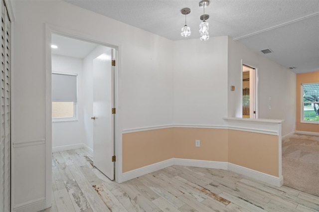 unfurnished dining area with light wood-type flooring and a textured ceiling