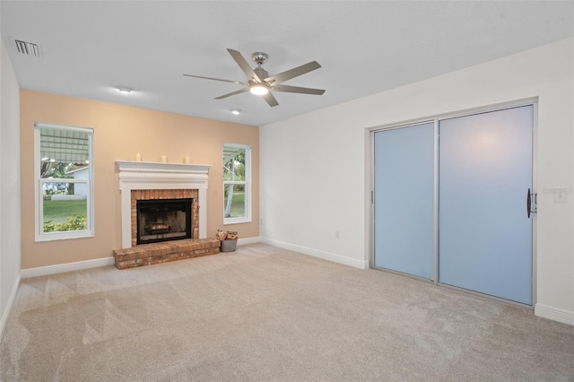 unfurnished living room featuring a brick fireplace, light colored carpet, and a wealth of natural light