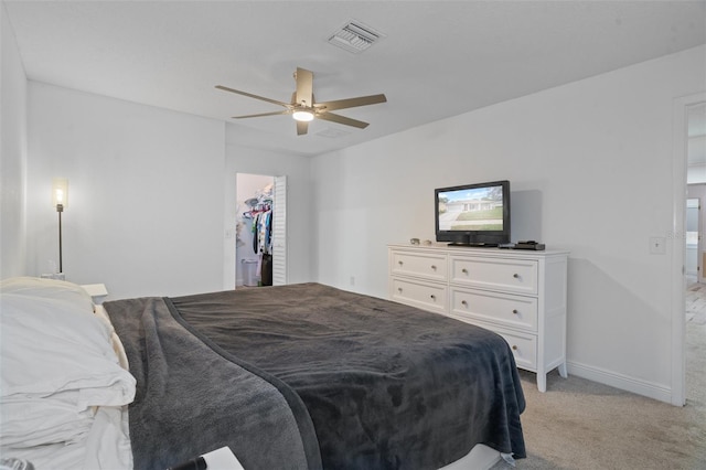 bedroom with ceiling fan, light colored carpet, a closet, and a spacious closet