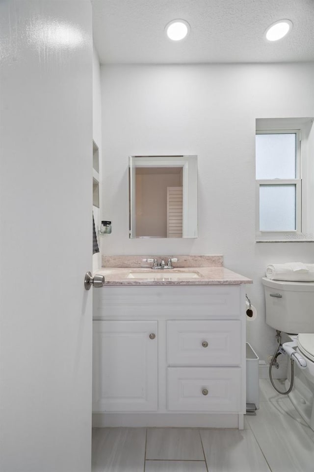 bathroom with toilet, vanity, and tile patterned flooring