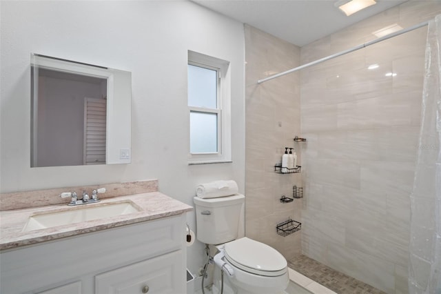 bathroom featuring toilet, vanity, and a tile shower