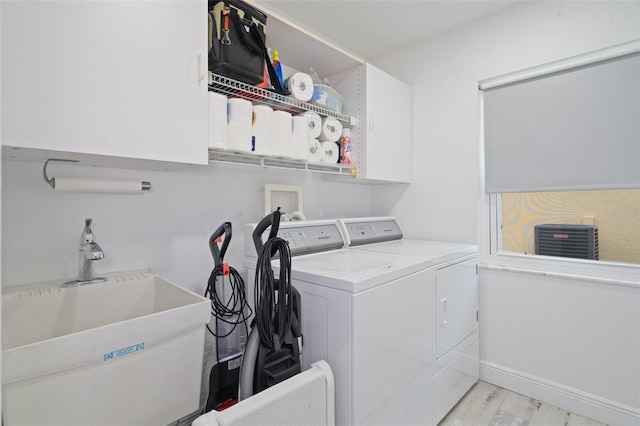 washroom featuring cabinets, sink, independent washer and dryer, and light hardwood / wood-style flooring