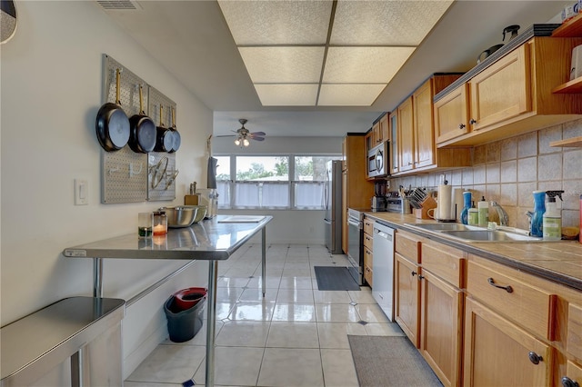 kitchen featuring appliances with stainless steel finishes, decorative backsplash, sink, ceiling fan, and light tile patterned floors