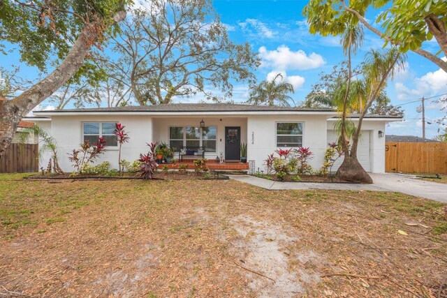 single story home with a front lawn, covered porch, and a garage