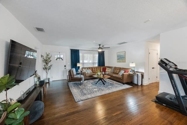 living room with a textured ceiling, ceiling fan, and dark hardwood / wood-style floors