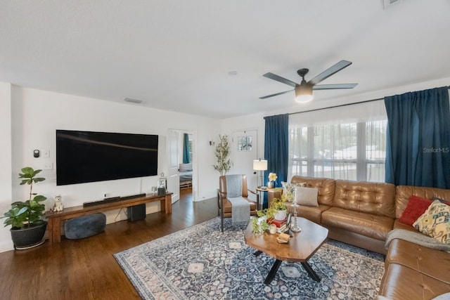 living room featuring ceiling fan and dark wood-type flooring