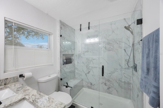 bathroom with a textured ceiling, toilet, vanity, and an enclosed shower