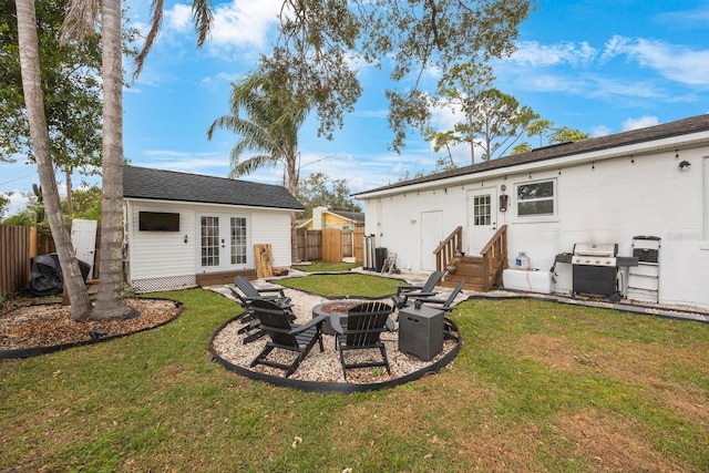 rear view of property with french doors, an outdoor fire pit, and a lawn