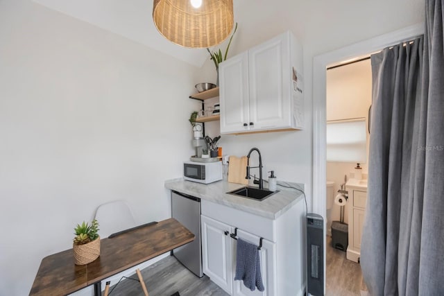 kitchen featuring sink, white cabinetry, dishwasher, and light wood-type flooring