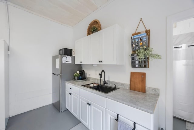 kitchen featuring wood ceiling, stainless steel fridge, sink, and white cabinetry