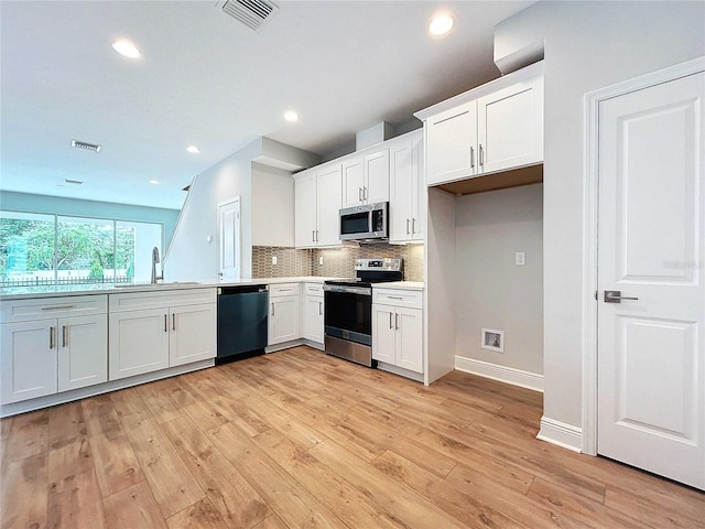 kitchen featuring tasteful backsplash, light hardwood / wood-style floors, sink, white cabinetry, and stainless steel appliances