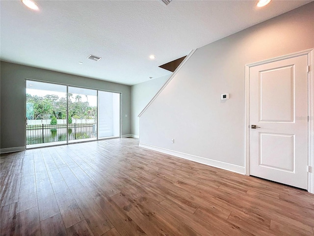 spare room with a textured ceiling and light wood-type flooring