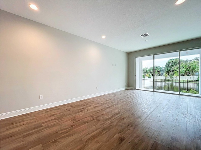 unfurnished room with hardwood / wood-style floors and a textured ceiling