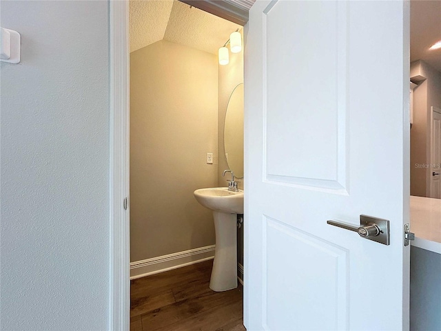 bathroom with lofted ceiling, a textured ceiling, and hardwood / wood-style flooring