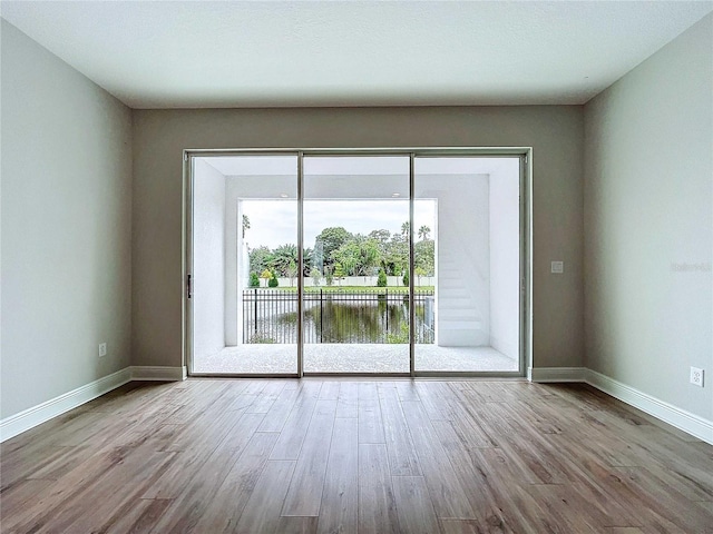 unfurnished room with a water view and light hardwood / wood-style floors