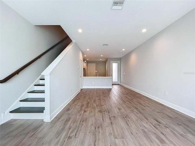 unfurnished living room featuring light wood-type flooring and a textured ceiling