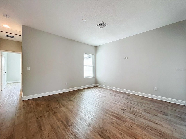 spare room featuring dark wood-type flooring and a textured ceiling