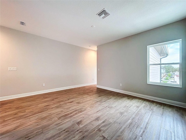 unfurnished room with wood-type flooring and a textured ceiling