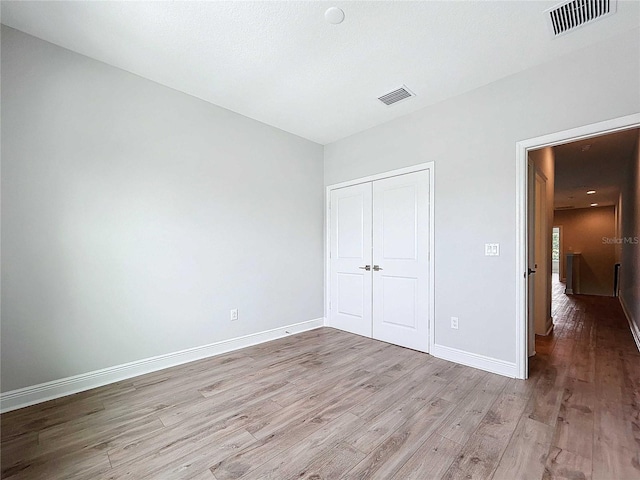 unfurnished bedroom with a closet and light hardwood / wood-style flooring