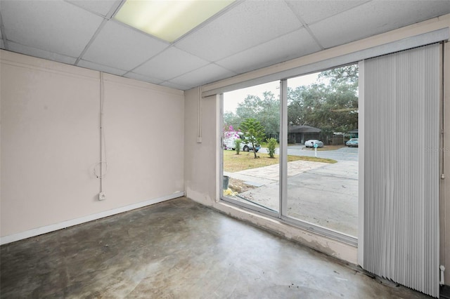 empty room with a paneled ceiling and concrete flooring