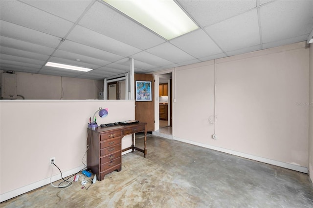 basement featuring a paneled ceiling and electric panel