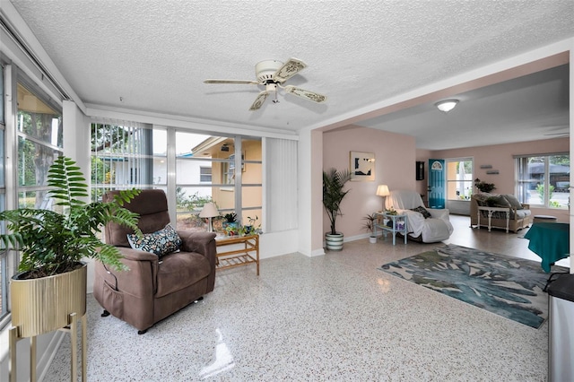 living room with ceiling fan and a textured ceiling