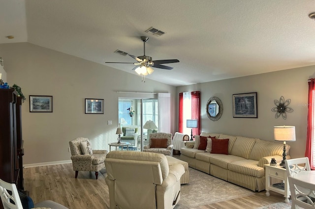 living room featuring lofted ceiling, a textured ceiling, ceiling fan, and light wood-type flooring