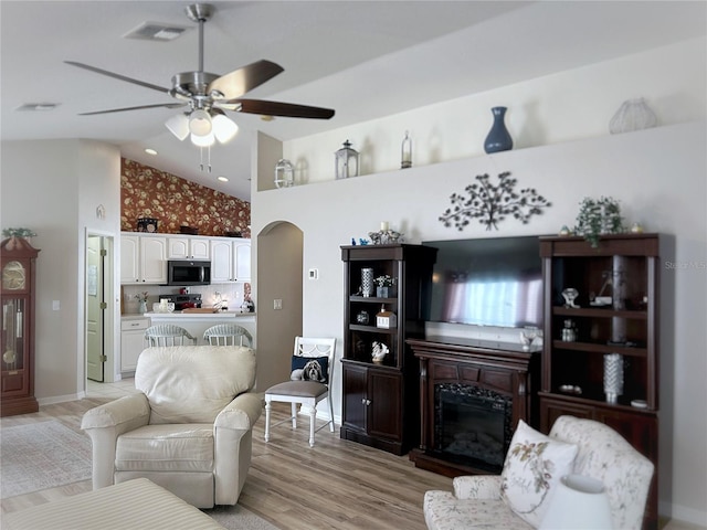 living room featuring high vaulted ceiling, ceiling fan, and light hardwood / wood-style flooring