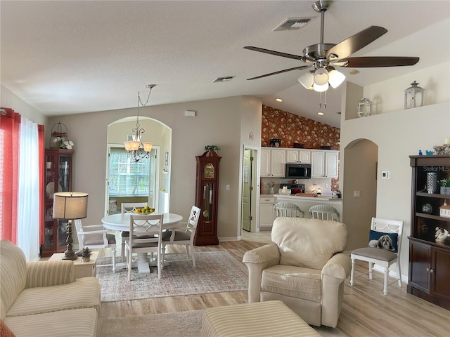 interior space featuring lofted ceiling, ceiling fan with notable chandelier, and light wood-type flooring