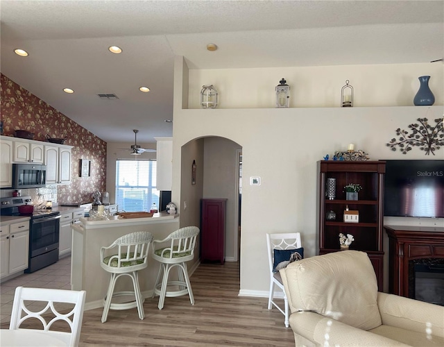 kitchen with ceiling fan, stainless steel appliances, white cabinets, vaulted ceiling, and kitchen peninsula