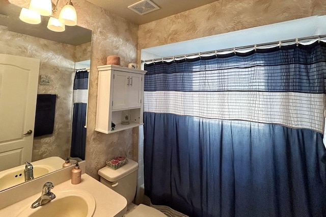 bathroom with toilet, sink, and a notable chandelier